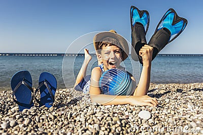 Boy has water polo ball and scuba gear on the beach. Looking at camera. Concept of travel, tourism, family Stock Photo