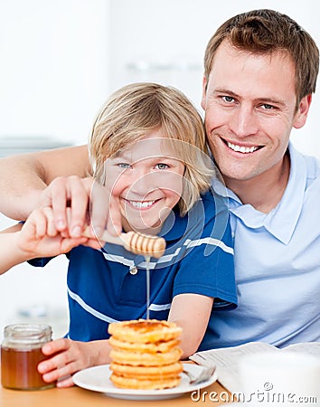 Happy boy and his father putting honey on waffles Stock Photo