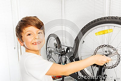 Happy boy repairing his bicycle wheel with spanner Stock Photo