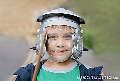 Happy boy wearing lobster-tailed pot helmet costume pretending to be a legionary soldier, Active kid playing outside in the park Stock Photo