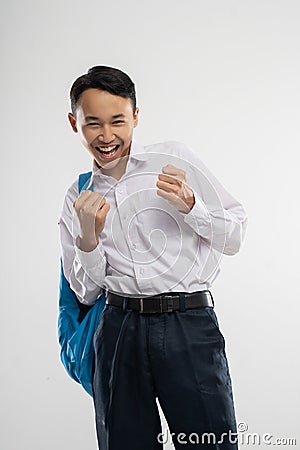 a happy boy wears a school uniform with excited hands gestures while carries a school bag Stock Photo