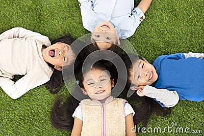 Boys and girls lying on green grass Stock Photo