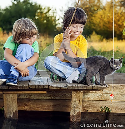 Happy boys go fishing on the river, Two children of the fisherman with a fishing rod on the shore of lake Stock Photo