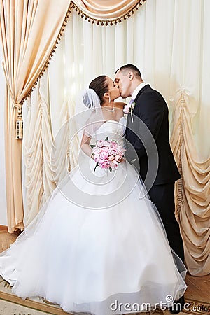 Happy bride and groom kissing on solemn registration Stock Photo