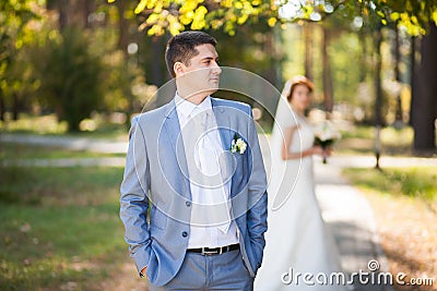 Happy bride, groom standing in green park, kissing, smiling, laughing. lovers in wedding day. happy young couple in love. Stock Photo