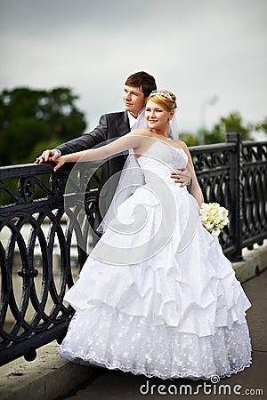 Happy bride and groom at wedding walk on bridge Stock Photo