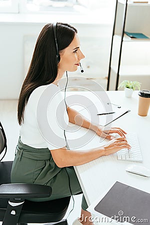 Happy broker in headset typing on Stock Photo
