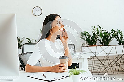 Happy broker touching headset while holding Stock Photo