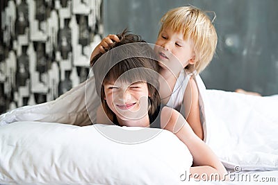 Happy brother with little brother lying in a bed together, kissing and hugging. Siblings. Little brother sleeping and seven years Stock Photo