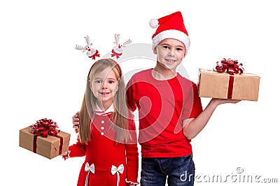 Happy brother with santa hat on his head and a sister with deer horns, holding the gift boxes in their hands. Concept Stock Photo