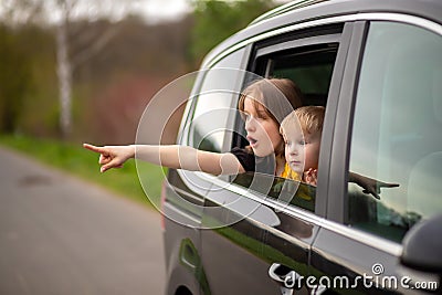 Happy brother and sister looking out car window Stock Photo