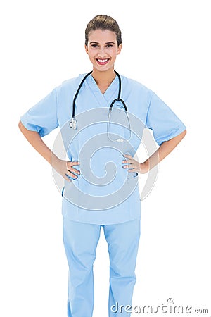 Happy brown haired nurse in blue scrubs posing with hands on the hips Stock Photo
