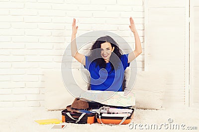 Happy brunete woman is packing suitcase at home. Stock Photo