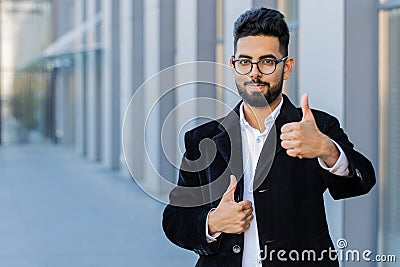 Happy business man showing thumbs up, like sign positive good positive feedback in city street Stock Photo