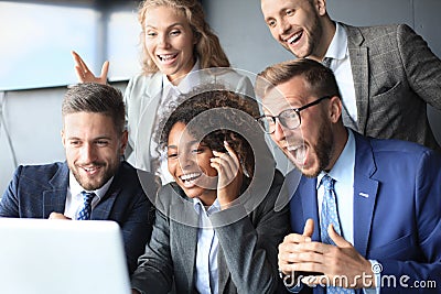 Happy business people laugh near laptop in the office. Successful team coworkers joke and have fun together at work. Stock Photo