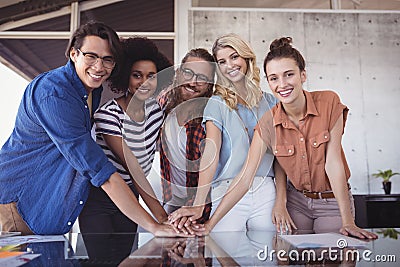 Happy business people stacking hands on table in creative office Stock Photo