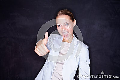 Happy business woman gesturing a success sign against black. Excited young business woman gesturing a thumbs up sign Stock Photo