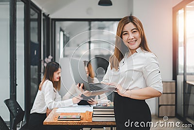 Happy business woman standing competently and smiling in open plan office Stock Photo