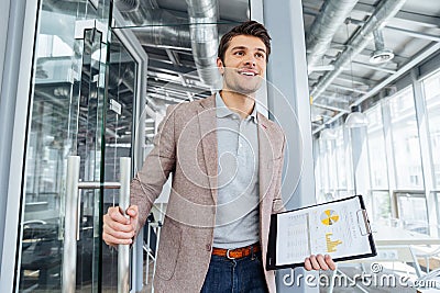 Happy businessman with business plan entering the door in office Stock Photo