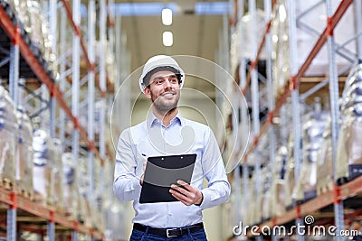 Happy businessman with clipboard at warehouse