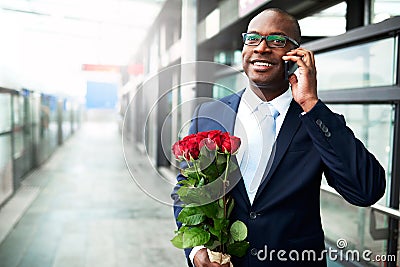 Happy Businessman with Flowers Calling on Phone Stock Photo