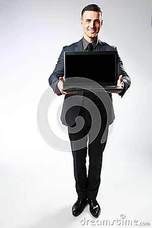 Happy businessman standing with laptop Stock Photo