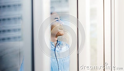 Happy Businessman Standing by the Window in Office. Looking away and Smiling. Dreaming for Success Stock Photo