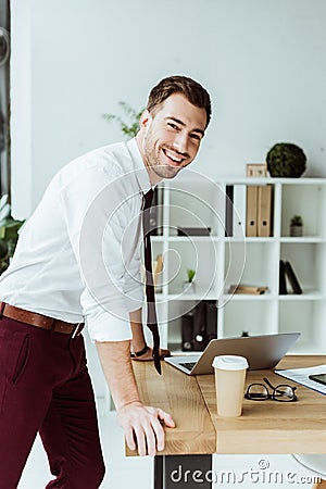 happy businessman standing at workplace with laptop and coffee Stock Photo