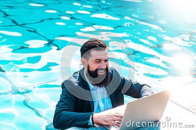 Happy businessman in suit with laptop in swimming pool. Funny business man relaxing with notebook. Crazy comic business. Stock Photo