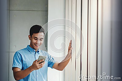 Happy Businessman Using Smartphone.Standing by the Window in Office Stock Photo