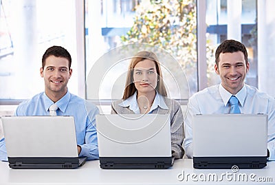 Happy businessteam working on individual laptops Stock Photo