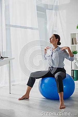 Happy businesswoman exercising on fitness balls in office Stock Photo