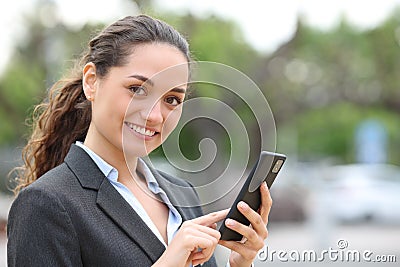 Happy businesswoman holds phone and looks at you Stock Photo