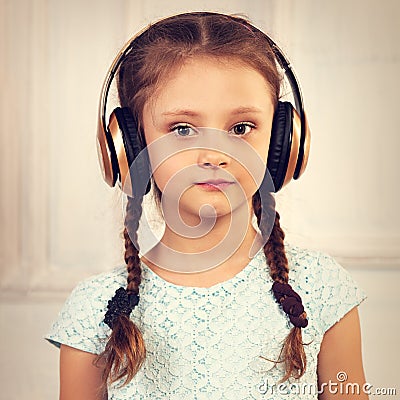 Happy calm serious kid girl in blue dress listening the music in Stock Photo