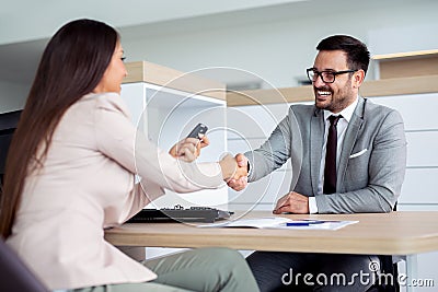 Happy car dealer and customer shake hands after successfully signed contract. Stock Photo