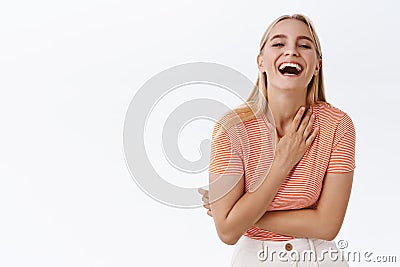 Happy and carefree, emotive blond alluring woman having fun, laughing out loud from joy and delight, touch chest smiling Stock Photo