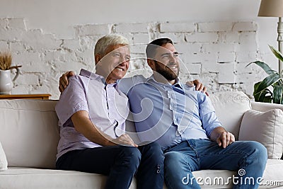 Happy carefree man hugs older father smile look into distance Stock Photo