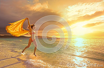 Happy carefree woman running in the sunset on the beach. Stock Photo