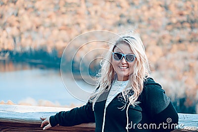 Happy carefree woman stands with blond hair blowing in wind at a scenic overlook in the Porcupine Mountains of Michigan Stock Photo