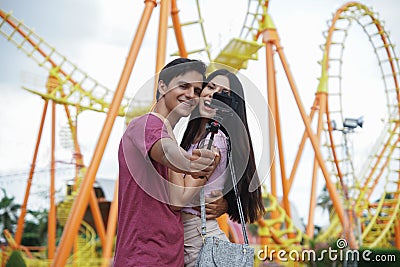 Happy Caucasian young couples take camera selfie photos together at theme park Stock Photo