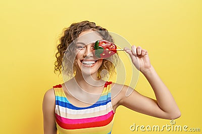 Playful girl hiding eye with strawberry candy lollipop. Stock Photo