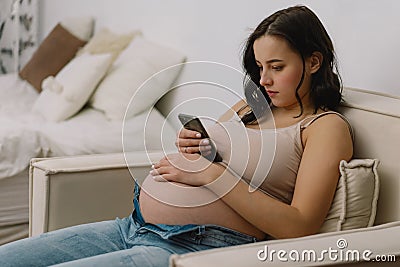 Happy charming pregnant woman using mobile phone. Pregnant Woman Stock Photo