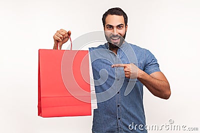 Happy cheerful businessman pointing finger at paper shopping bags in hand, satisfied pleased with shopping, big sale Stock Photo