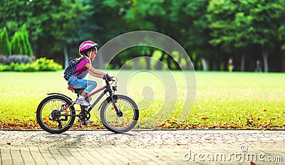 Happy cheerful child girl riding a bike in Park in nature Stock Photo