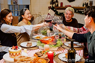 Happy and Cheerful group of extended Asian family has a toast and cheer during Christmas dinner at home. Celebration holiday Stock Photo