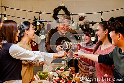 Happy and Cheerful group of extended Asian family has a toast and cheer during Christmas dinner at home. Celebration holiday Stock Photo