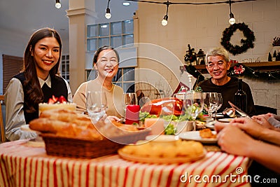 Happy and Cheerful group of extended Asian family talking and smiling during Christmas dinner at home. Celebration holiday Stock Photo