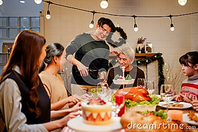 Happy and Cheerful group of extended Asian family talking and smiling during Christmas dinner at home. Celebration holiday Stock Photo