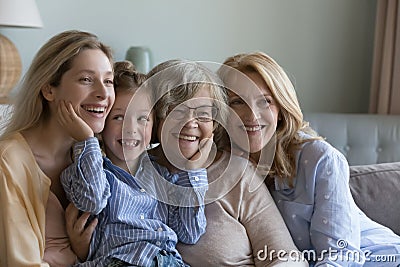 Happy kid, young, mature and elder women relaxing on sofa Stock Photo