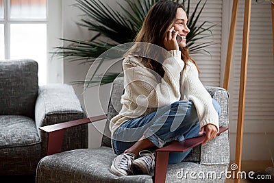 Happy cheerful young woman talking on the phone at home Stock Photo